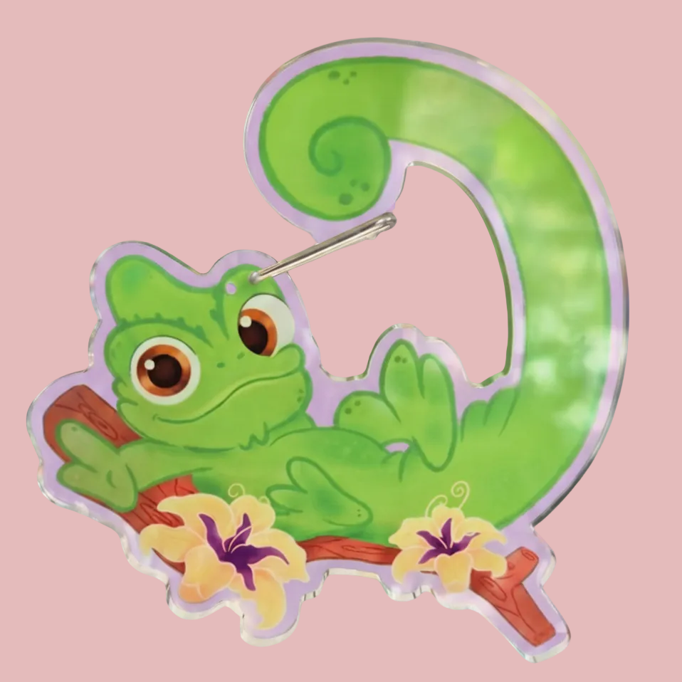 Green lizard character on a letter 'Q' with flowers on a purple background, featuring 'Imagination Station' branding.