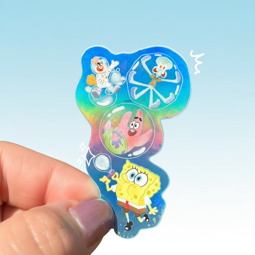 Holographic sticker with cartoon characters held by a hand against a green leafy background