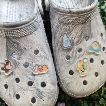 Pair of gray clogs with decorative stickers on a grassy background