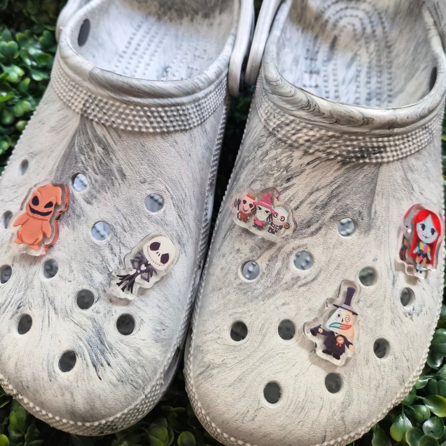 Pair of gray crocs with decorative stickers on a grass background